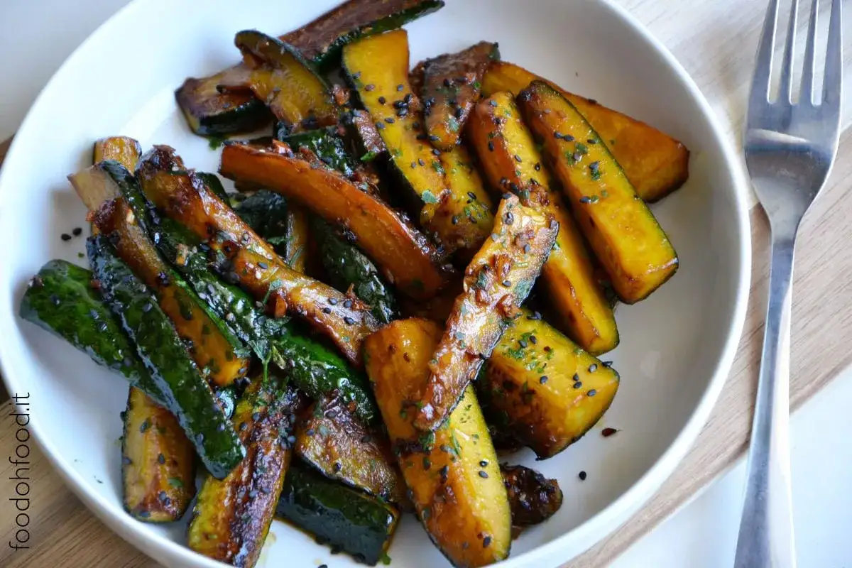 Zucchine in padella caramellate, cosparse di semi di sesamo nero e prezzemolo fresco. Un contorno saporito e colorato.