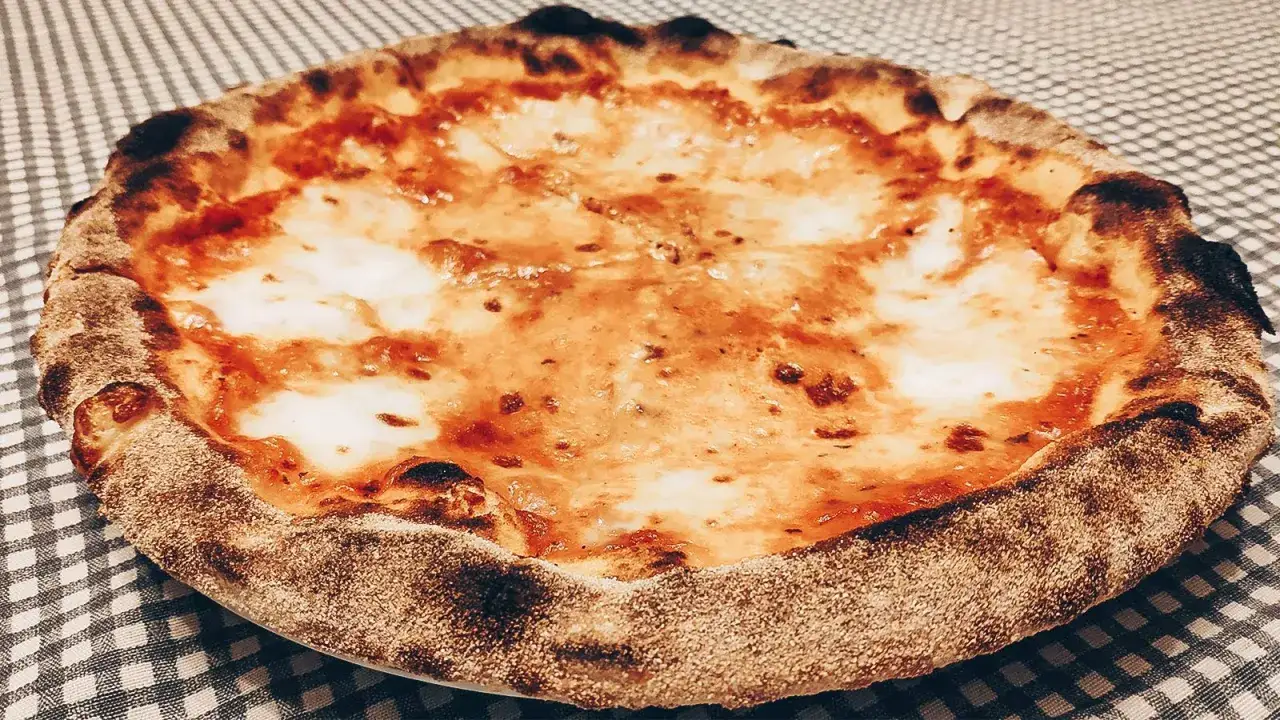 Pizza fatta in casa con crosta dorata e mozzarella filante, pronta per essere gustata.