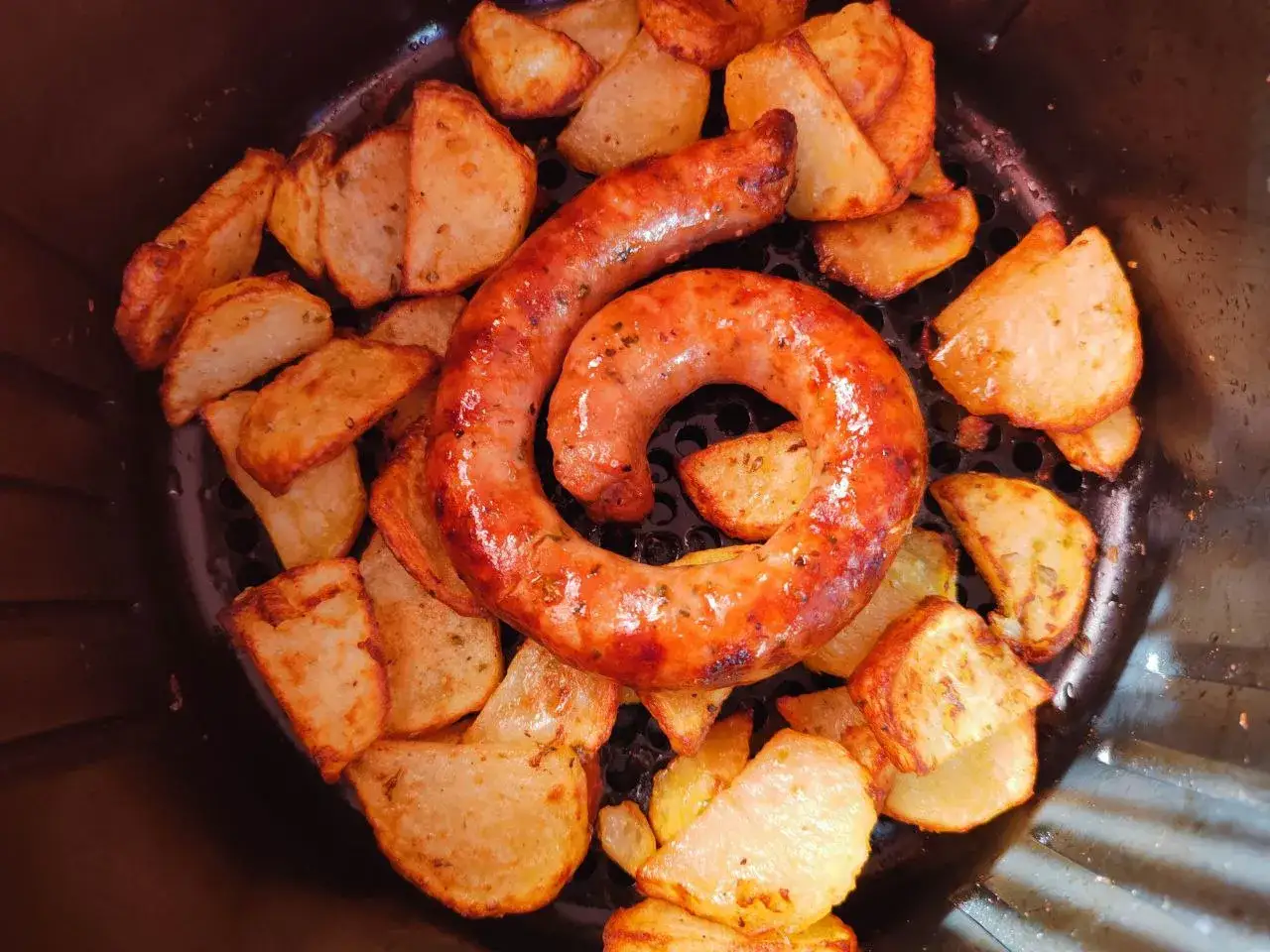 Salsiccia arrotolata e patate croccanti nella friggitrice ad aria. Un pasto veloce e gustoso.