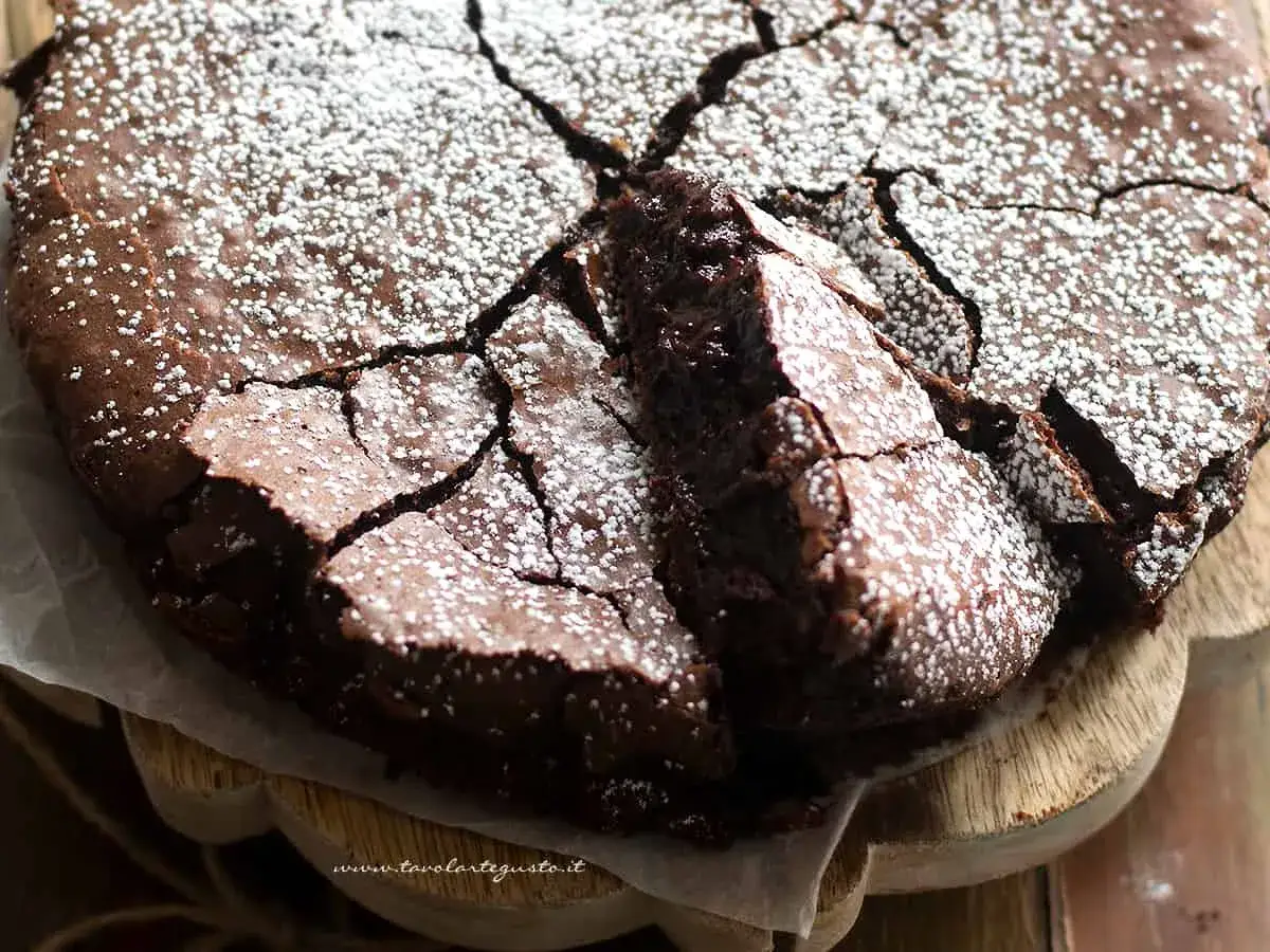 Una deliziosa torta al cioccolato fondente, con una crosta crepata e cosparsa di zucchero a velo, pronta per essere gustata.