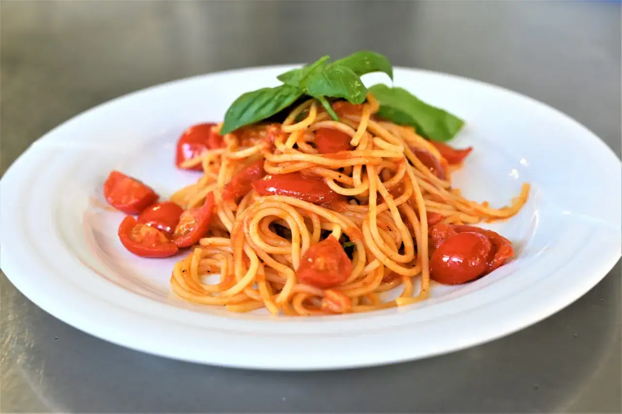 Un piatto di spaghetti al pomodoro fresco, conditi con pomodorini succosi e basilico profumato, un classico della cucina italiana.