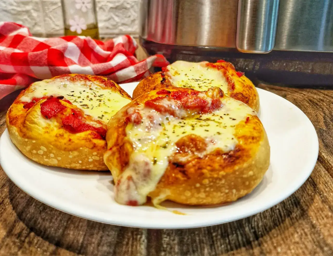 Tre pizzette fatte in casa, dorate e filanti, su un piatto bianco.