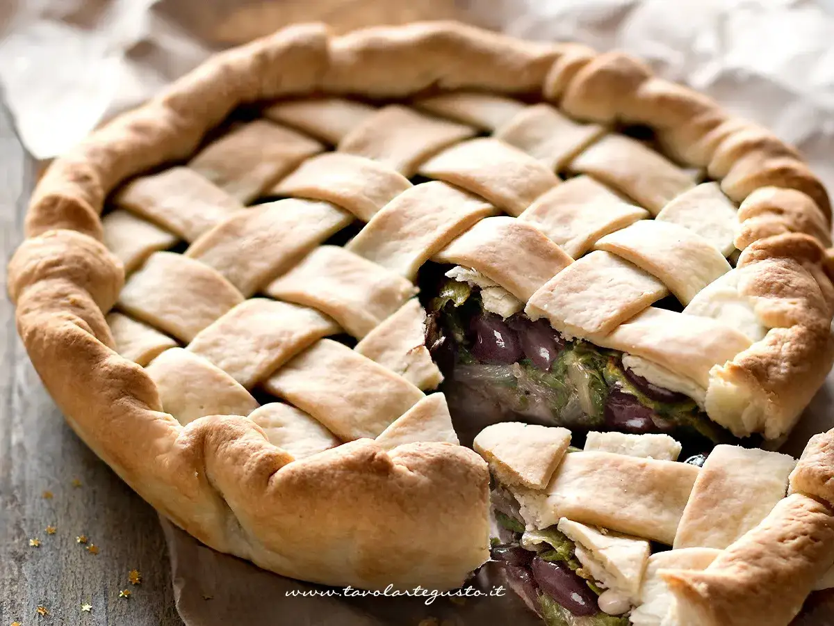 Pizza di scarola con un intreccio dorato di pasta, ripiena di verdure e olive.