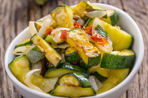Zucchine in padella, dorate e saporite, con cipolla e pomodoro. Un contorno leggero e gustoso, pronto da gustare.