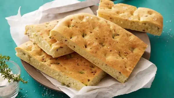 Focaccia con lievito istantaneo, dorata e soffice, guarnita con erbe aromatiche e sale grosso. Perfetta per un pasto veloce e gustoso.