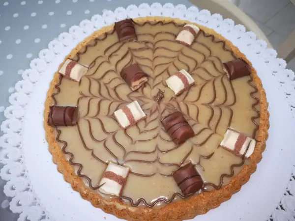 Torta Kinder Bueno con decorazione a ragnatela e pezzi di cioccolato.