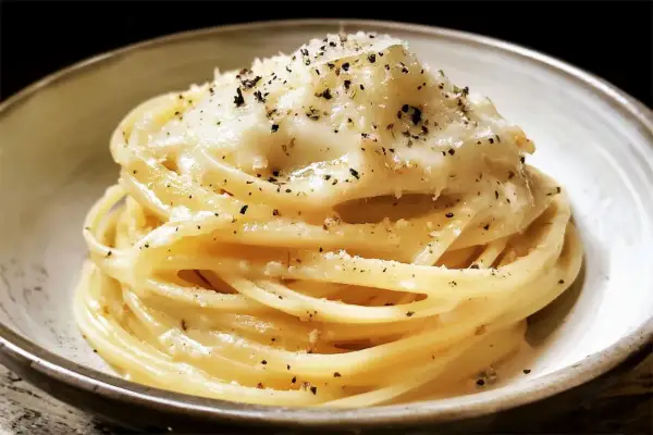 Un piatto di spaghetti fumanti, conditi con la cremosità del cacio e pepe e una generosa spolverata di pepe nero.