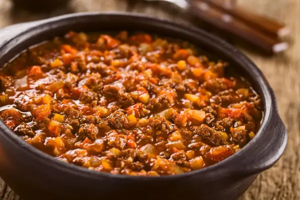 Un saporito ragù di cinghiale in una ciotola di terracotta, pronto per essere gustato con la pasta.