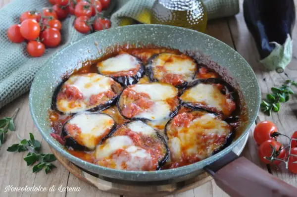 Fette di melanzane cotte in padella con pomodoro e mozzarella filante, un classico piatto di melanzane alla pizzaiola.