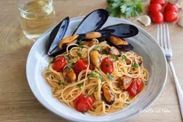 Spaghetti con le cozze e pomodorini, un piatto di mare profumato e colorato, pronto per essere gustato con un bicchiere di vino bianco.