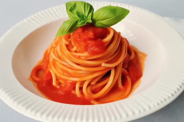 Un piatto di spaghetti al pomodoro fresco, guarnito con foglie di basilico profumato.