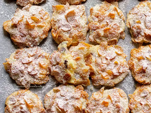 Biscotti croccanti, simili a rose del deserto, ricoperti di zucchero a velo e fiocchi di mais.